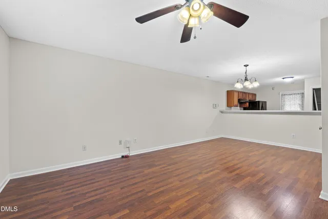 a view of an empty room with wooden floor fireplace and a window