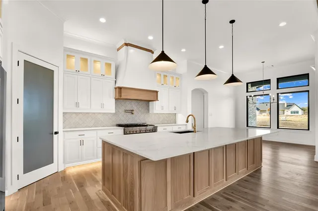 a kitchen that has a lot of cabinets in it and wooden floors