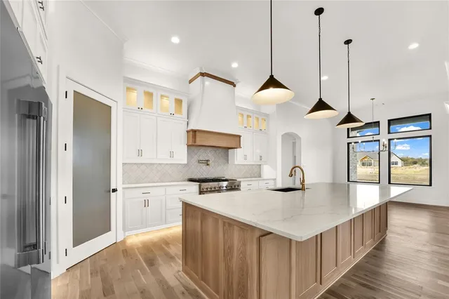 a kitchen with stainless steel appliances a sink a center island a stove a refrigerator and a window