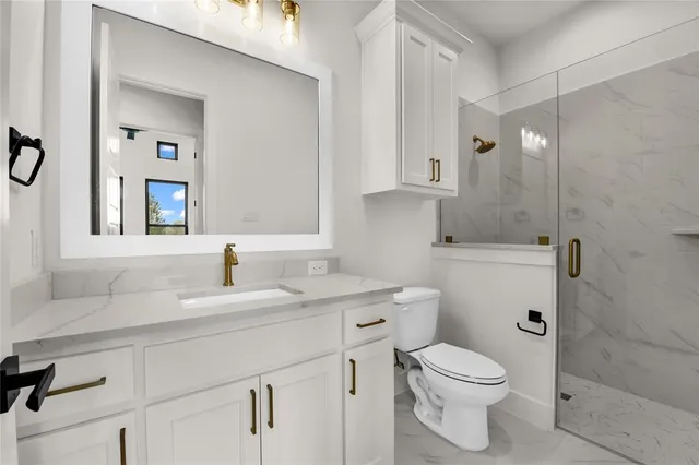 a bathroom with a granite countertop toilet sink and mirror