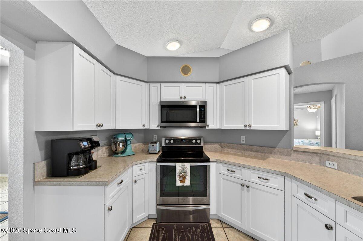 5975 Aruin Street Cocoa, FL 32927 - Photo 13 of 70 a kitchen with granite countertop white cabinets and black appliances