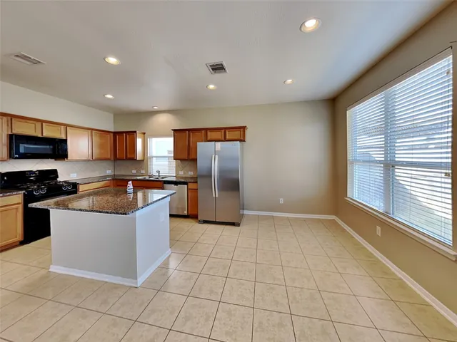 a large kitchen with stainless steel appliances granite countertop a large counter top and a stove top oven