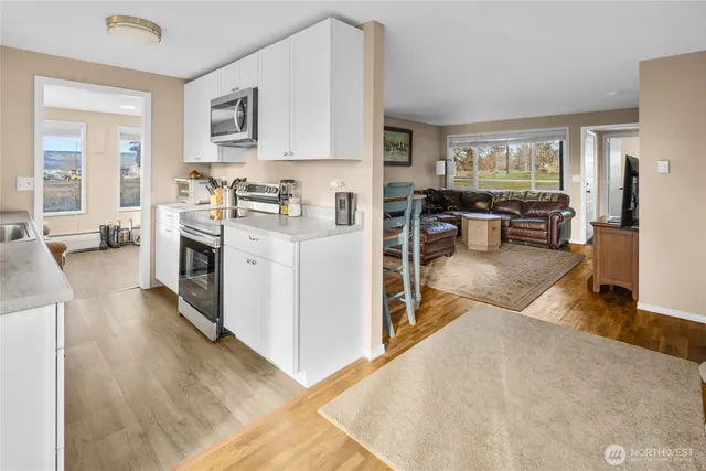 a view of living room kitchen with stainless steel appliances cabinets and a window