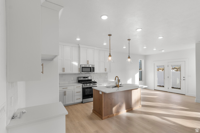 537 South Rivergate Drive Logan, UT 84321 - Photo 6 of 20 Bright kitchen and living area featuring white cabinetry, stainless steel appliances, a wood-finish island with a countertop, recessed lighting, and light wood-finish flooring