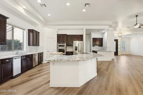 a large kitchen with stainless steel appliances granite countertop a large counter top and oven a sink with wooden floor