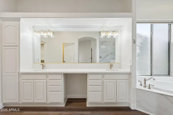 a bathroom with a double vanity sink mirror and bathtub