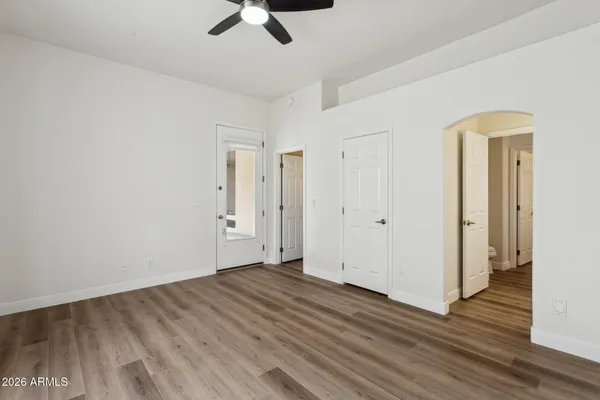 an empty room with wooden floor fan and windows