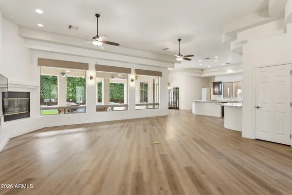 a view of an empty room with wooden floor and a kitchen