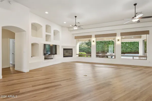 a view of an empty room with a window and wooden floor