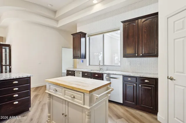 a kitchen with stainless steel appliances kitchen island granite countertop a stove top oven a refrigerator a sink and dishwasher with wooden floor