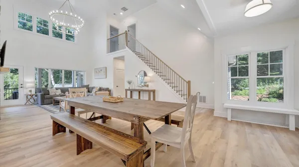 a kitchen with stainless steel appliances granite countertop a refrigerator a sink dishwasher a dining table and chairs with wooden floor