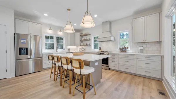 a large kitchen with granite countertop a white table and chairs in it
