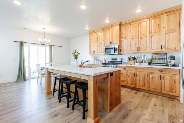 349 West 3085 South Logan, UT 84321 - Photo 6 of 37 Expansive kitchen featuring wood-finish cabinetry, stainless steel appliances, a center island with countertop seating, and light-toned flooring