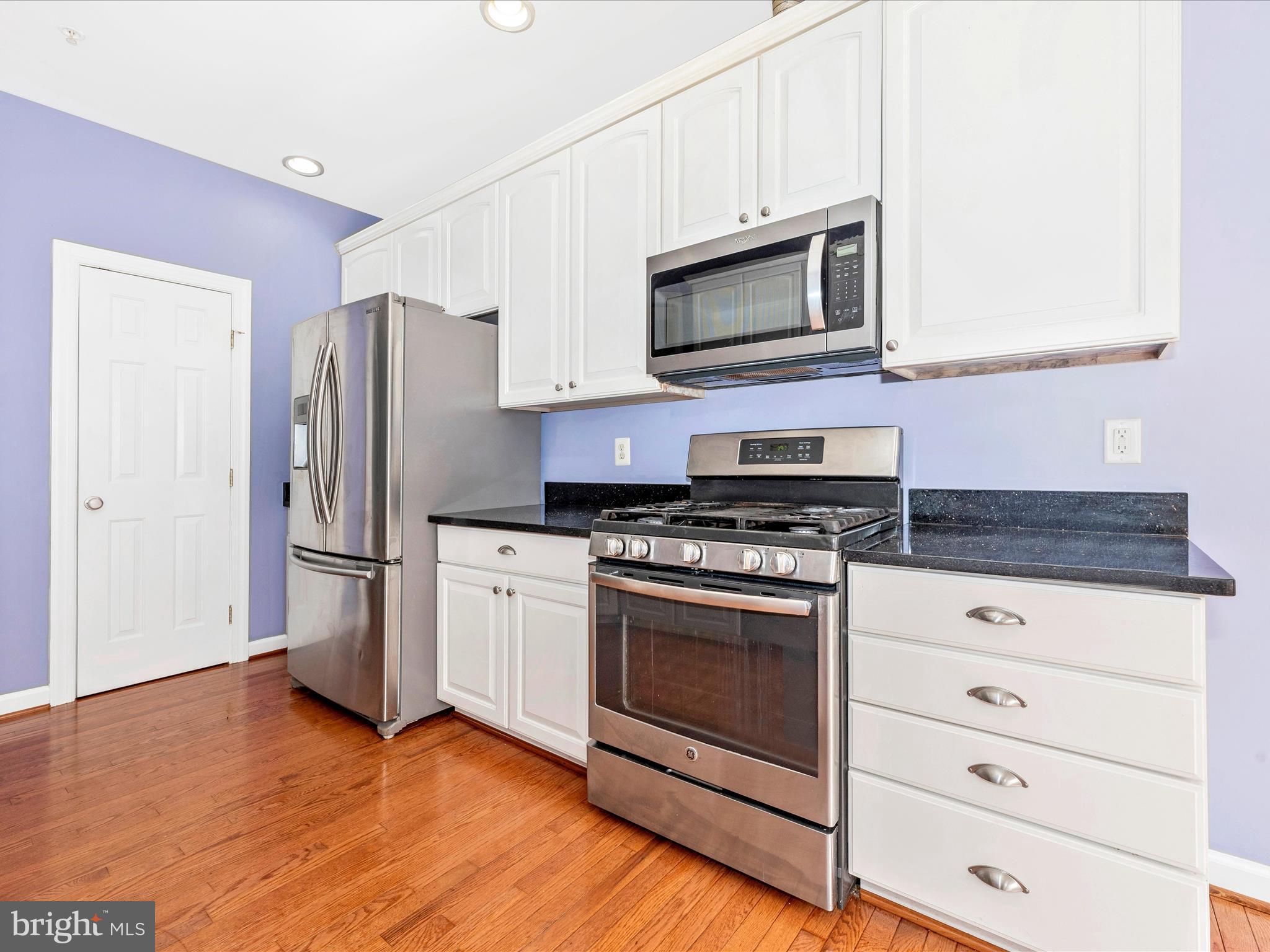 10811 Wadsworth Road Woodstock, MD 21163 - Photo 19 of 66 a kitchen with stainless steel appliances white cabinets a stove a microwave and a refrigerator
