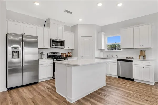 a kitchen with granite countertop a refrigerator and a stove top oven