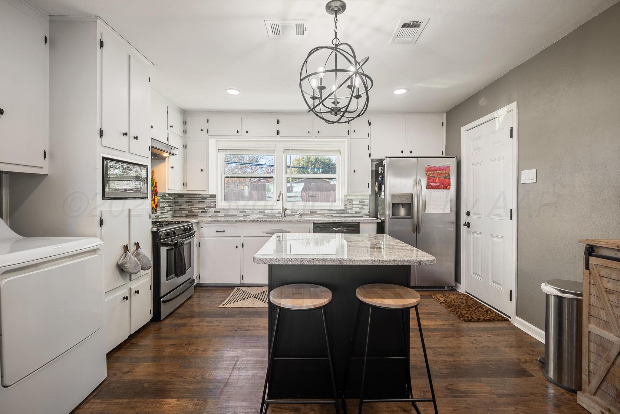 2220 Southeast 19th Avenue Amarillo, TX 79103 - Photo 9 of 25 a kitchen with stainless steel appliances a stove a sink dishwasher and a refrigerator with wooden floor