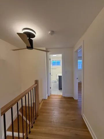 a view of a hallway with wooden floor and chandelier