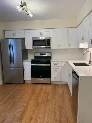 a kitchen with stainless steel appliances a sink cabinets and wooden floor