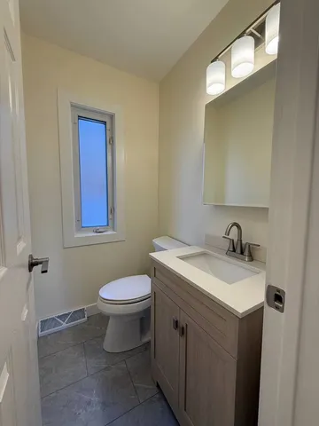 a bathroom with a granite countertop toilet and a sink