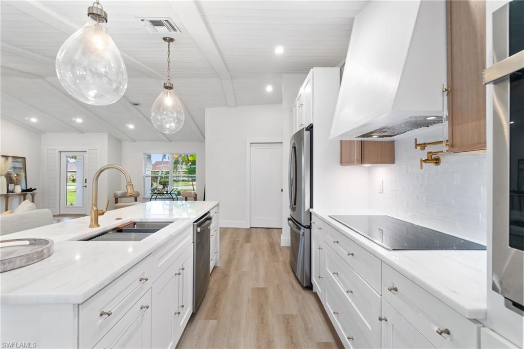 548 Ibis Way Naples, FL 34110 - Photo 14 of 45 a large white kitchen with a large island oven a sink stainless steel appliances and cabinets