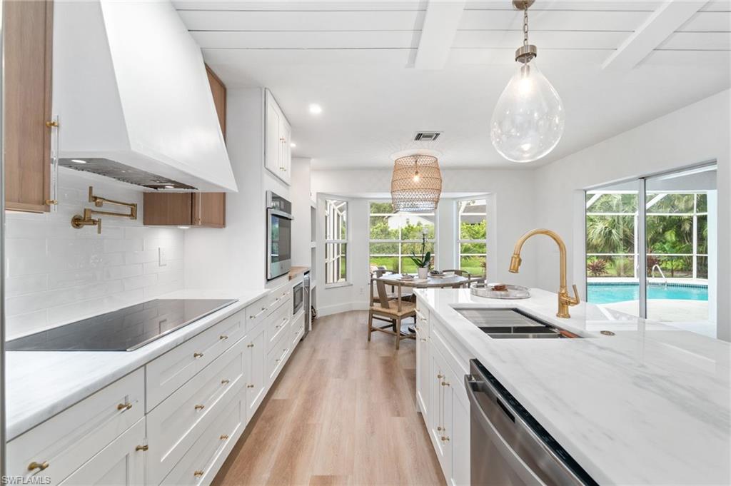 548 Ibis Way Naples, FL 34110 - Photo 15 of 45 a kitchen with granite countertop a stove and a wooden floors