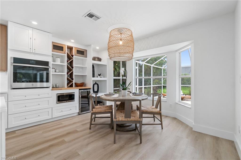 548 Ibis Way Naples, FL 34110 - Photo 17 of 45 a dining room with wooden floor a chandelier a wooden table and chairs