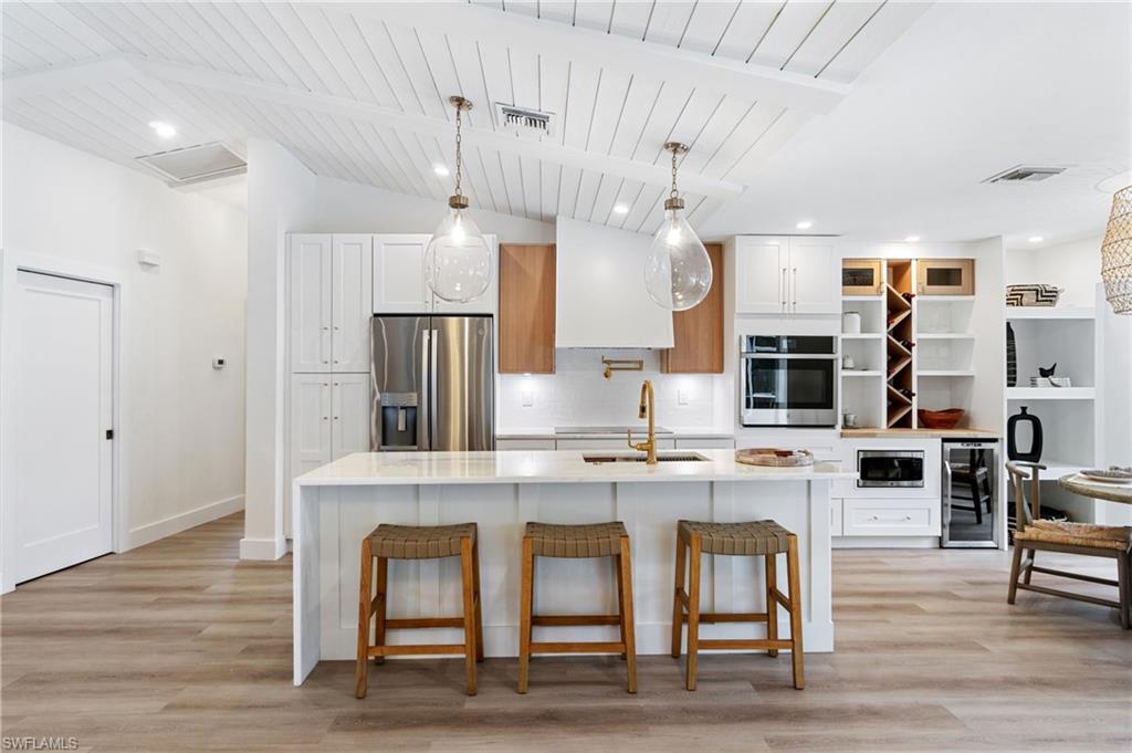 548 Ibis Way Naples, FL 34110 - Photo 3 of 45 a kitchen with stainless steel appliances a dining table chairs refrigerator and cabinets