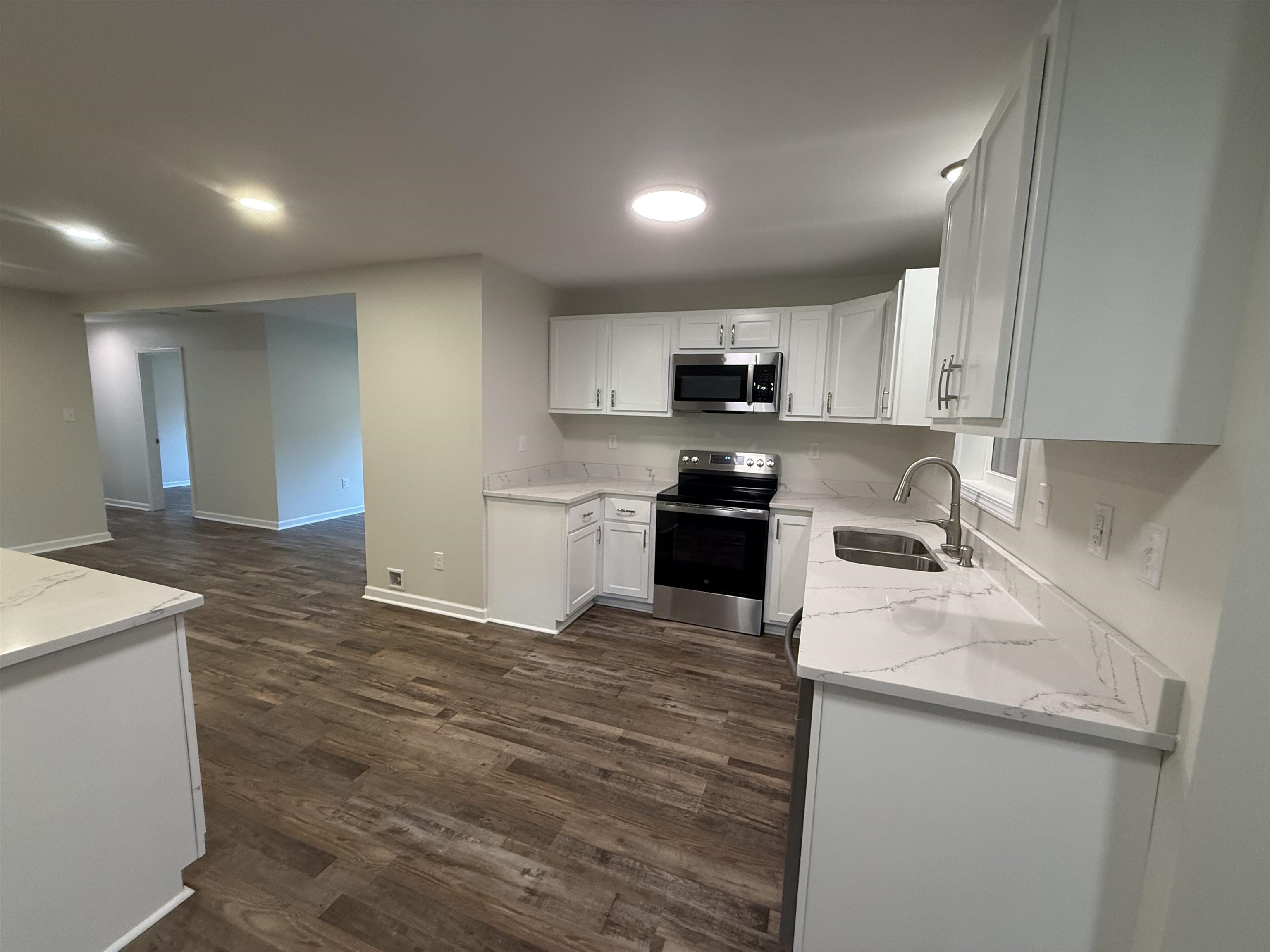 1835 Pleasant Grove Road Moscow, TN 38057 - Photo 9 of 34 Modern kitchen featuring white cabinetry, light-toned countertops, stainless steel appliances, and wood-finish flooring