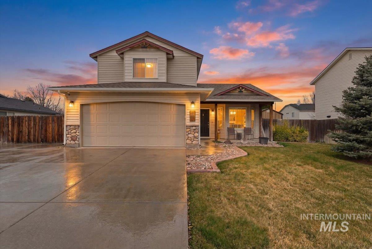 View of front of home with stone siding, an attached garage, concrete driveway, and covered porch
