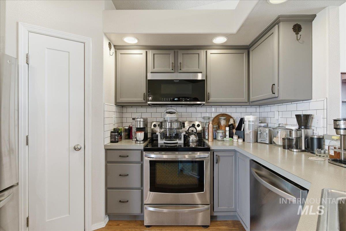 1896 West Ridge Pointe Avenue Nampa, ID 83651 - Photo 15 of 49 Kitchen with gray cabinets, stainless steel appliances, light countertops, light wood finished floors, and backsplash