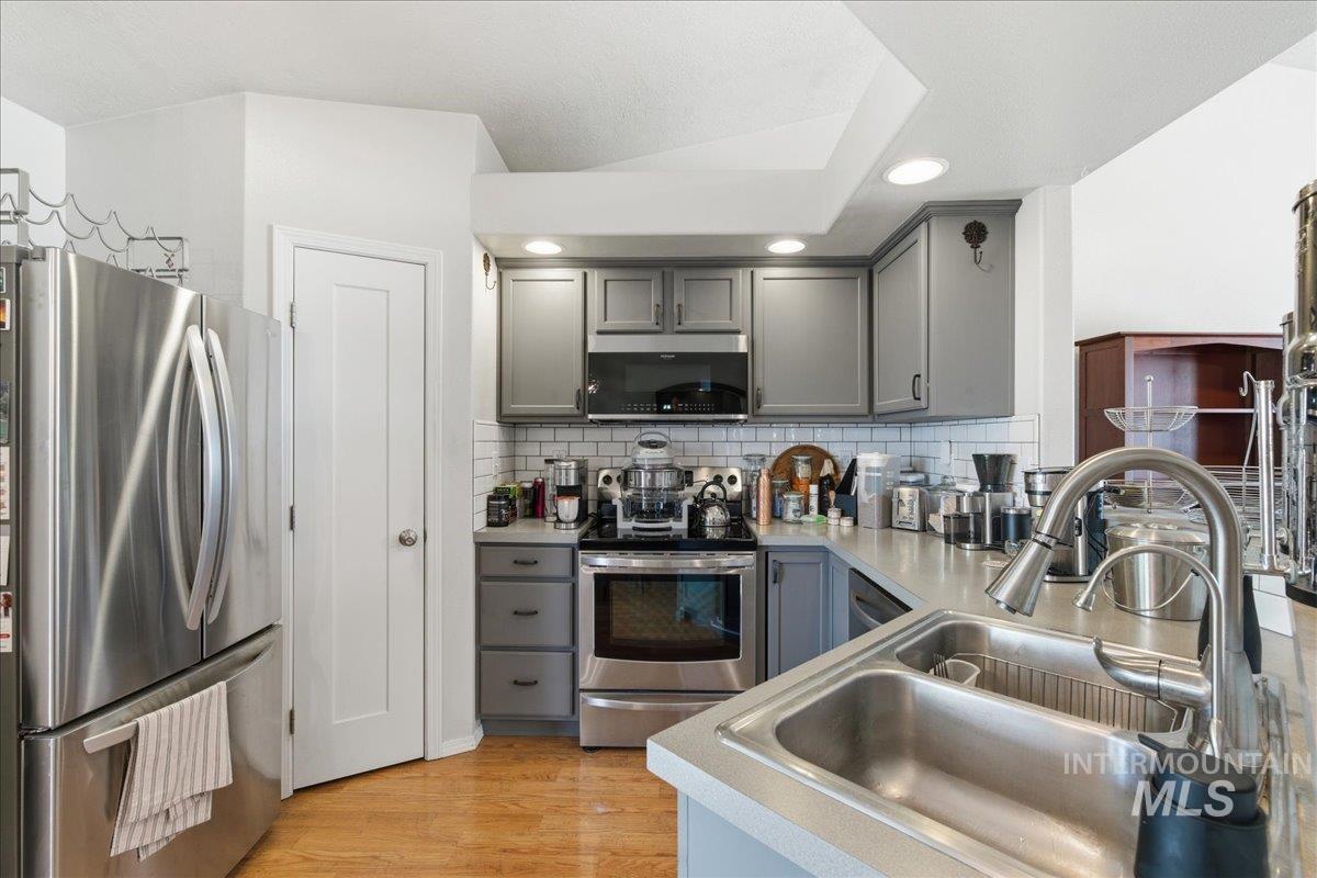 1896 West Ridge Pointe Avenue Nampa, ID 83651 - Photo 18 of 49 Kitchen with stainless steel appliances, gray cabinetry, light wood-style flooring, light countertops, and recessed lighting