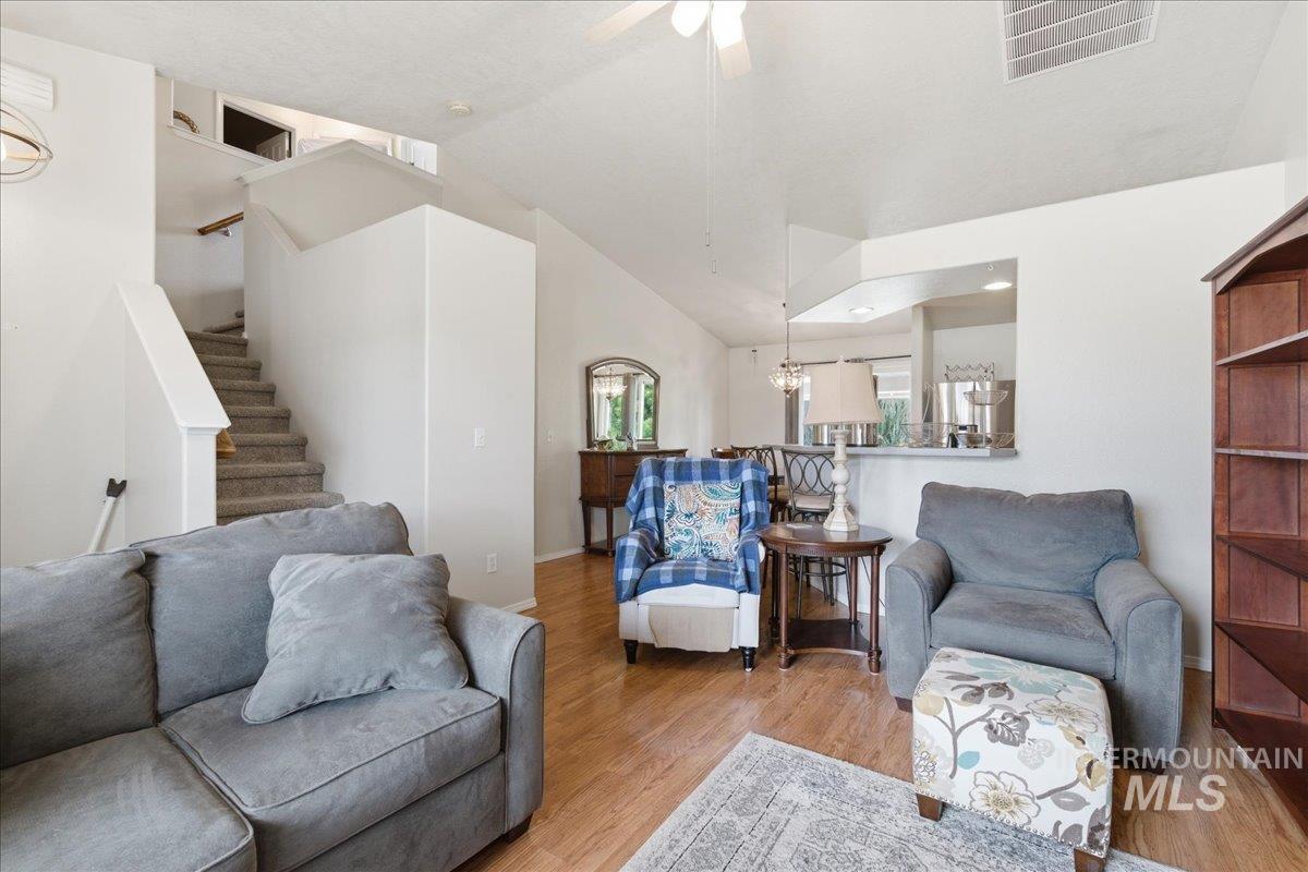 1896 West Ridge Pointe Avenue Nampa, ID 83651 - Photo 9 of 49 Living area featuring lofted ceiling, wood finished floors, a ceiling fan, and a chandelier