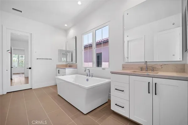 a spacious bathroom with a double vanity sink a mirror and a bathtub