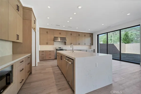 a large kitchen with stainless steel appliances granite countertop a large counter top a stove and a refrigerator
