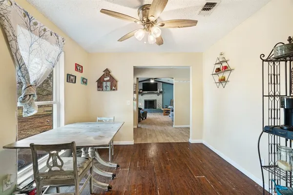 a view of a livingroom and a dining room with wooden floor a chandelier fan