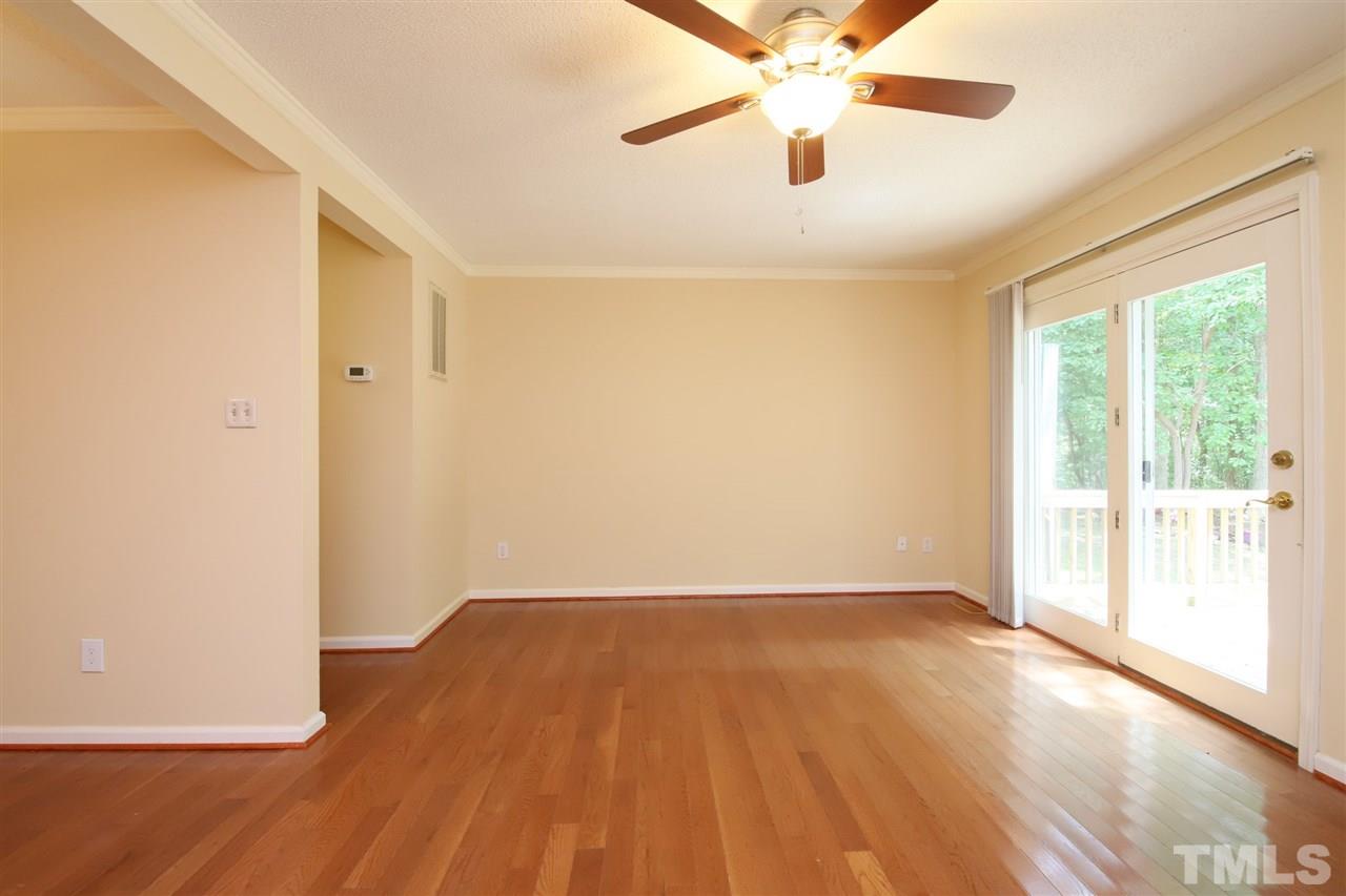 6708 Chauncey Drive Raleigh, NC 27615 - Photo 8 of 25 an empty room with wooden floor fan and windows