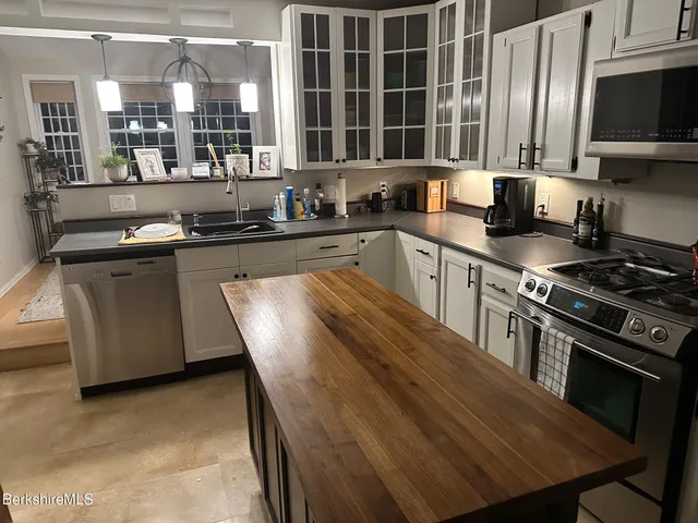 a kitchen with stainless steel appliances granite countertop a stove a sink and a microwave