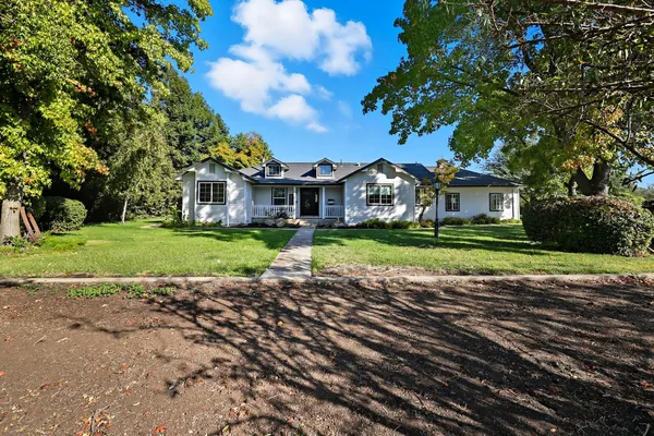 a view of a house with a big yard and large trees