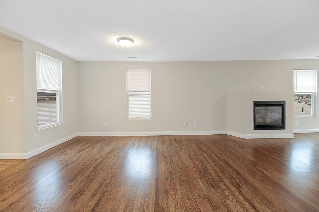23 Marcella Street, Unit 2 Boston, MA 02119 - Photo 6 of 26 a view of an empty room with wooden floor fireplace and a window