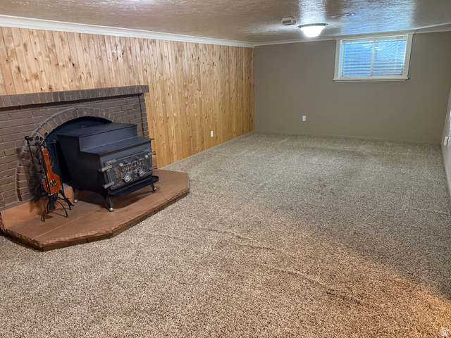 362 East 9150th Street South Sandy, UT 84070 - Photo 35 of 41 Below grade area with wood walls, carpet flooring, a wood stove, crown molding, and a textured ceiling