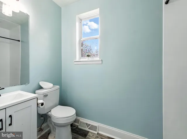 a white toilet sitting next to a white sink and vanity