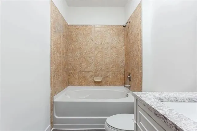 a bathroom with a granite countertop bathtub toilet and sink