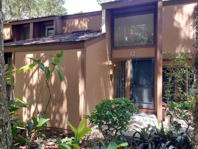 a vase with flowers sitting on a table in front of a house