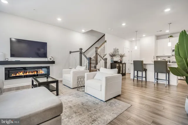 a living room with couches and a flat screen tv with kitchen view