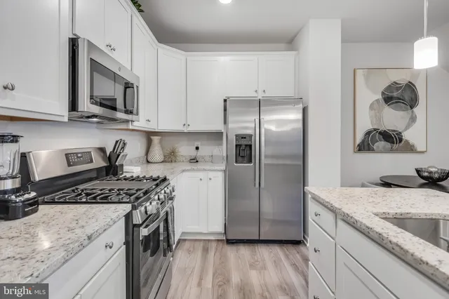 a kitchen with granite countertop a refrigerator stove and microwave with wooden floor