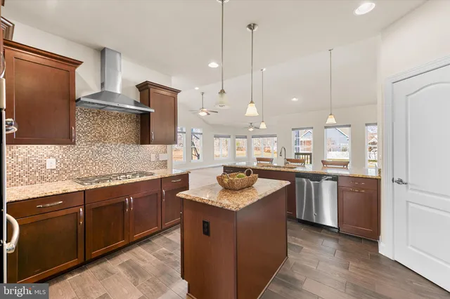 a kitchen with granite countertop kitchen island stainless steel appliances a refrigerator a stove a sink a center island and chairs