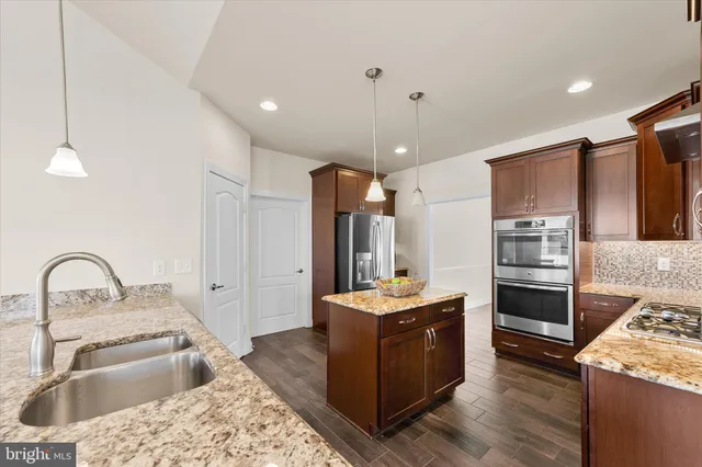 a kitchen with stainless steel appliances granite countertop a sink a stove and a refrigerator