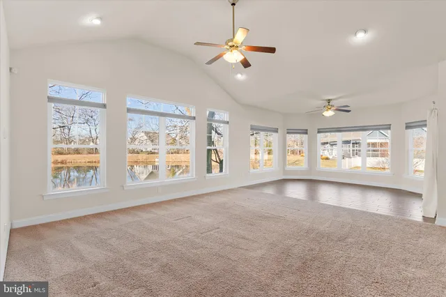 a view of an empty room with a window and kitchen view