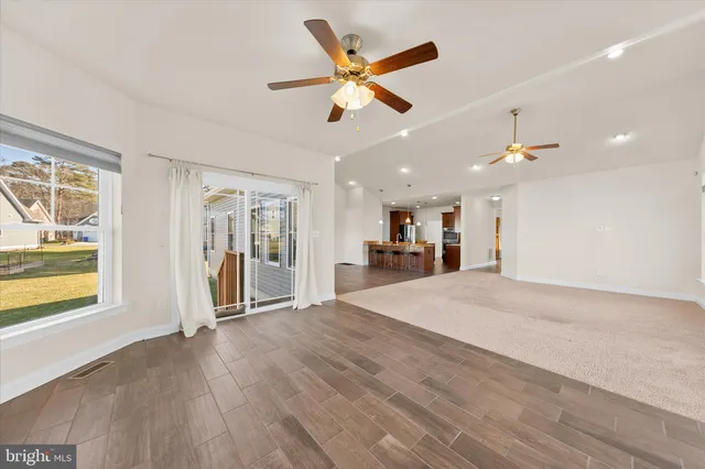 a view of empty room with wooden floor and ceiling fan