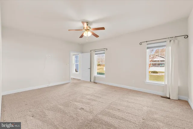an empty room with windows and fan